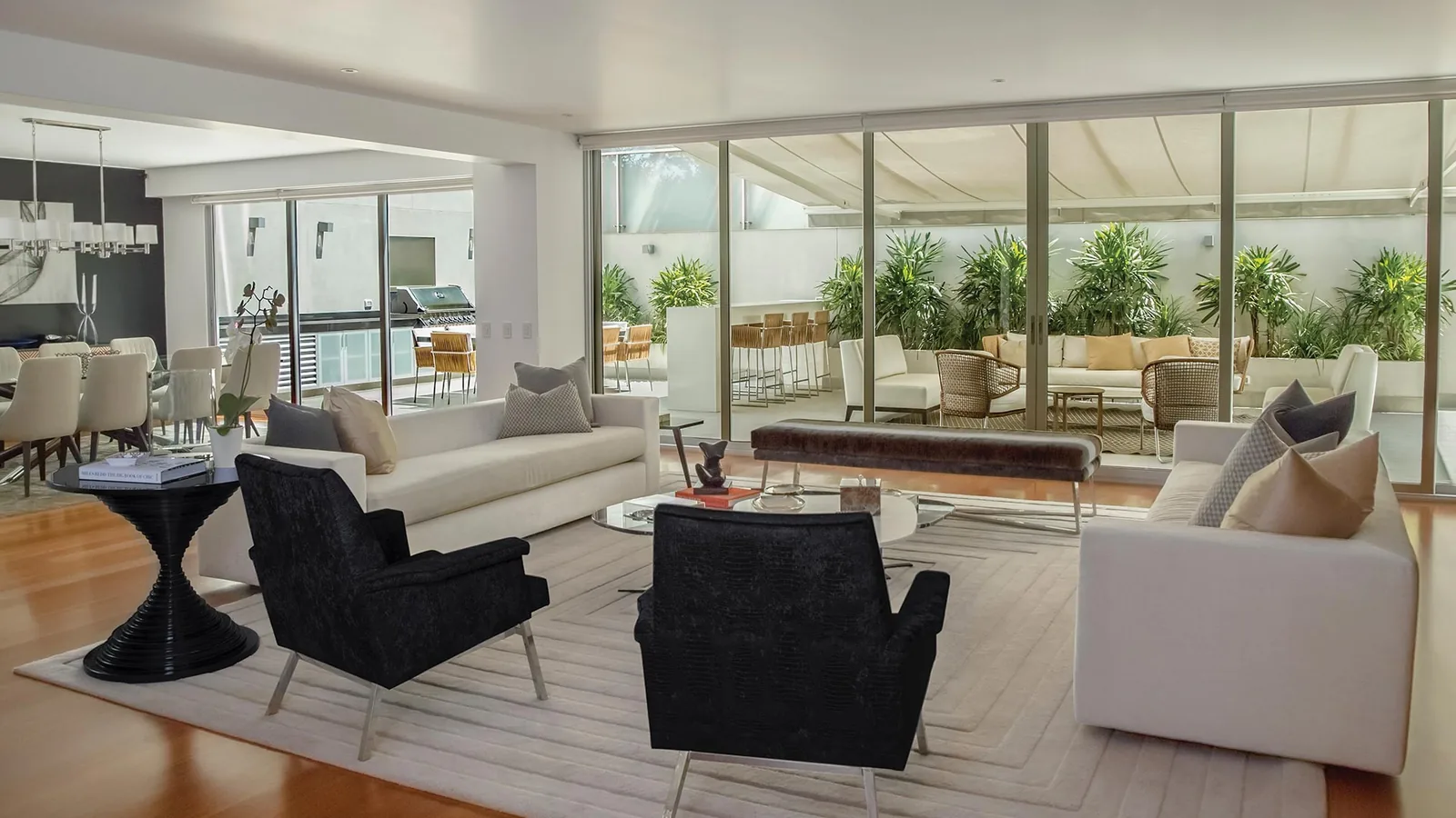 Helle Lounge mit Sesseln und Sofa vor einer Glasfront
